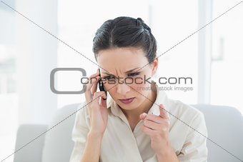 Frowning stylish brunette businesswoman making a phone call