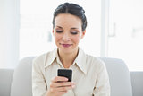 Happy stylish brunette businesswoman using her mobile phone