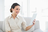 Cheerful stylish brunette businesswoman looking at her tablet pc