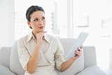 Pensive stylish brunette businesswoman holding a tablet pc
