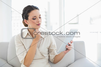 Thoughtful stylish brunette businesswoman looking at a tablet pc