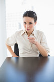 Stern stylish brunette businesswoman posing pointing at camera with her finger