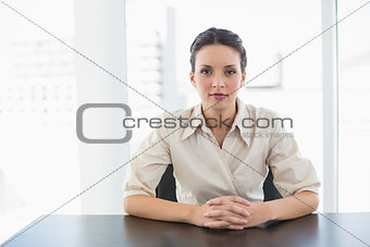 Serious stylish brunette businesswoman looking at camera and joining her hands