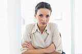 Stern stylish brunette businesswoman looking at camera and crossing her arms
