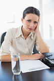 Frowning stylish brunette businesswoman sitting and holding her head