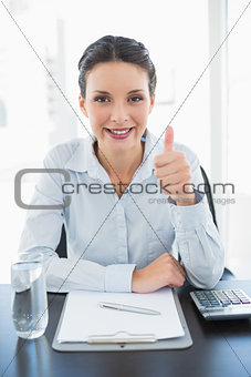 Pleased stylish brunette businesswoman giving thumb up