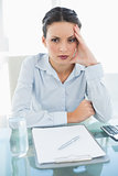 Bored stylish brunette businesswoman holding her head and looking away