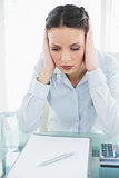 Upset stylish brunette businesswoman holding her head and looking away
