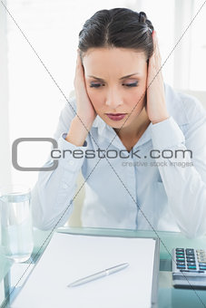 Upset stylish brunette businesswoman holding her head and looking away