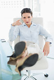 Frowning stylish brunette businesswoman relaxing with feet up
