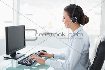 Smiling stylish brunette operator using a computer