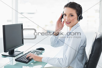 Pretty stylish brunette operator using a computer and answering a call