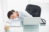 Tired stylish brunette businesswoman sleeping on her desk