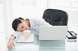 Sleepy stylish brunette businesswoman lying on her desk