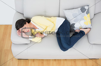 Peaceful casual brunette in yellow cardigan sleeping on the couch