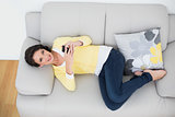 Content casual brunette in yellow cardigan using a mobile phone
