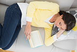 Relaxed casual brunette in yellow cardigan reading a book