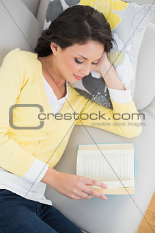 Peaceful casual brunette in yellow cardigan reading a book