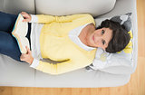 Cheerful casual brunette in yellow cardigan reading a book
