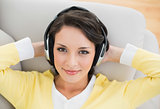 Smiling casual brunette in yellow cardigan enjoying music