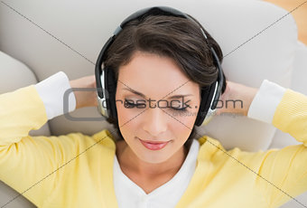 Peaceful casual brunette in yellow cardigan enjoying music