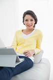 Pleased casual brunette in yellow cardigan using a tablet pc