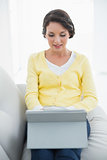 Thoughtful casual brunette in yellow cardigan using a tablet pc