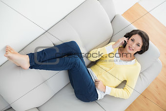Beautiful casual brunette in yellow cardigan making a phone call