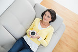 Calm casual brunette in yellow cardigan holding a mug of coffee