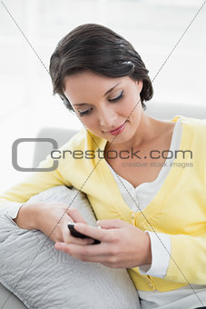 Attractive casual brunette in yellow cardigan using a mobile phone