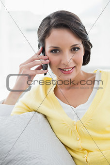 Happy casual brunette in yellow cardigan calling with her mobile phone