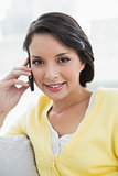 Cheerful casual brunette in yellow cardigan calling with her mobile phone