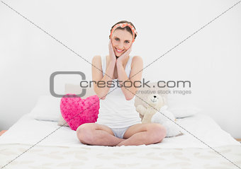 Pretty young woman sitting on her bed