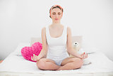 Meditating young woman sitting on her bed