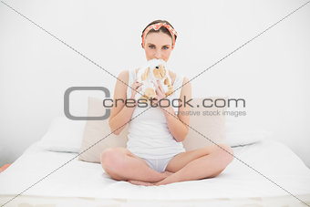 Young woman hiding her mouth with a cuddly toy