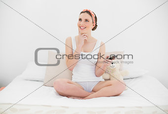 Thinking young woman holding her smartphone
