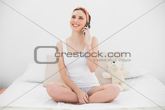 Smiling woman phoning on her bed