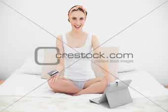Smiling young woman using her tablet looking into the camera