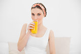 Woman drinking a glass of orange juice looking into the camera