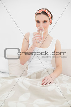 Woman drinking a glass of water looking into the camera