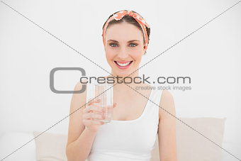 Young woman holding a glass of water smiling into the camera