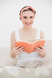 Young woman holding a book smiling into the camera