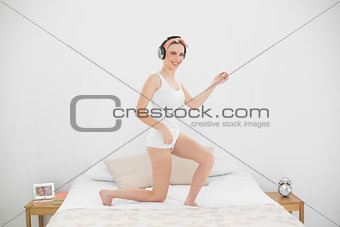 Pretty woman playing air guitar on her bed