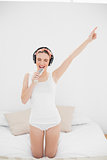 Young woman pretending to sing while listening to music with closed eyes
