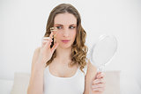 Woman holding an eyelash curler and a mirror