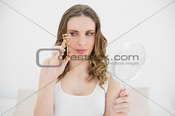 Woman holding an eyelash curler and a mirror
