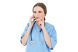 Thinking woman doctor phoning with her smartphone