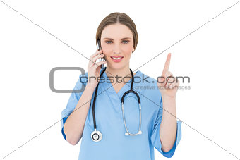 Pretty woman doctor phoning and pointing with her finger