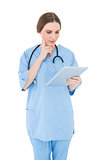 Thinking female doctor holding a tablet