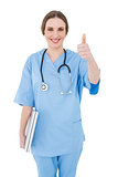 Young female doctor holding a white notebook and putting thumbs up